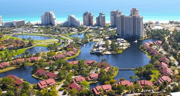 A coastal resort area with multiple high-rise buildings, a marina, and residential housing with red roofs.