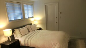 A bedroom with a bed, two bedside lamps, a nightstand, a window with blinds, and a door. - DETACHED GUEST HOUSE: Walk To Town, 1030 Sq Ft, 1 BR/1.5 BA, Mt. Tam Vie (Mill Valley)