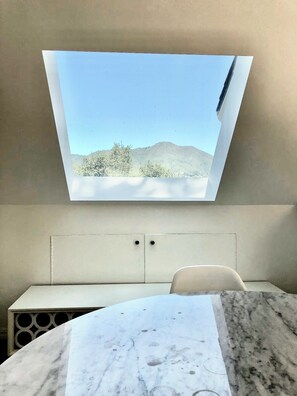 A room with a bed, a window with a view of a mountain, and a marble table. - DETACHED GUEST HOUSE: Walk To Town, 1030 Sq Ft, 1 BR/1.5 BA, Mt. Tam Vie (Mill Valley)