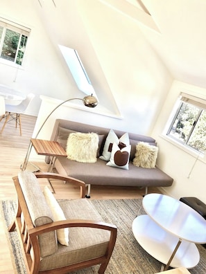 A modern living room with a sofa, a round table, and a wooden bench. - DETACHED GUEST HOUSE: Walk To Town, 1030 Sq Ft, 1 BR/1.5 BA, Mt. Tam Vie (Mill Valley)
