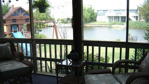 A covered outdoor seating area with wicker furniture and a view of a lake and buildings in the background. - "He Crab She Crab"  Waterfront Home w/Beach, Bay&Backyard Fun. Perfect for Kids! (Virginia Beach)