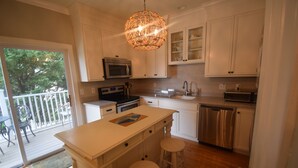 Una cocina con gabinetes blancos, electrodomésticos de acero inoxidable y una isla de madera con taburetes.
