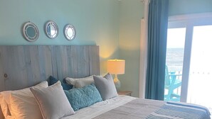 A neatly made bed with a striped blanket, a wooden headboard, and a nightstand with a lamp. - Perfect in every Way: Nothing to do but relax (Kure Beach)