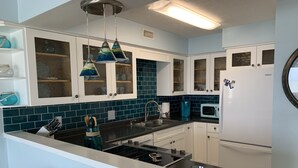 A modern kitchen with white cabinets, a stainless steel sink, and a microwave. - Perfect in every Way: Nothing to do but relax (Kure Beach)