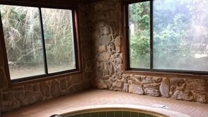 A hot tub in a stone-walled room with large windows. - Perfect in every Way: Nothing to do but relax (Kure Beach)