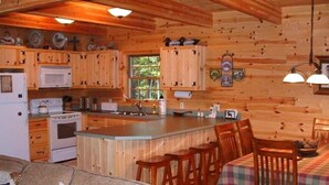 Een gezellige keuken in cottage-stijl met houten kasten, een centraal eiland en een eethoek met geruit tafelkleed.