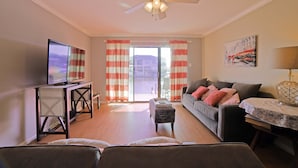 A living room with a television, sofa, and a ceiling fan. - Perfect ground floor unit ready to entertain your family vacation.  (Corpus Christi)