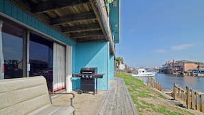 A wooden deck with a bench, a grill, and a view of a marina with boats. - Perfect ground floor unit ready to entertain your family vacation.  (Corpus Christi)