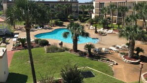 Un complexe hôtelier doté d’une piscine entourée de palmiers et de chaises longues.