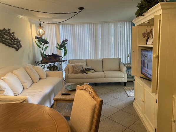 Una sala de estar con un sofá color crema, una mesa de centro de madera y un televisor sobre un mueble.