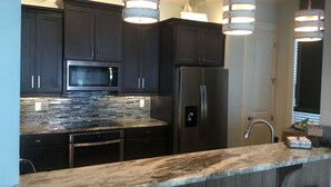Una cocina moderna con armarios oscuros, un refrigerador de acero inoxidable, un microondas y un salpicadero de azulejos.