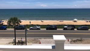 Vista de la playa con coches aparcados a lo largo de la carretera y un cielo despejado.