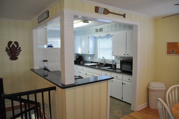 A compact kitchen with white cabinets, a black countertop, and a small island.