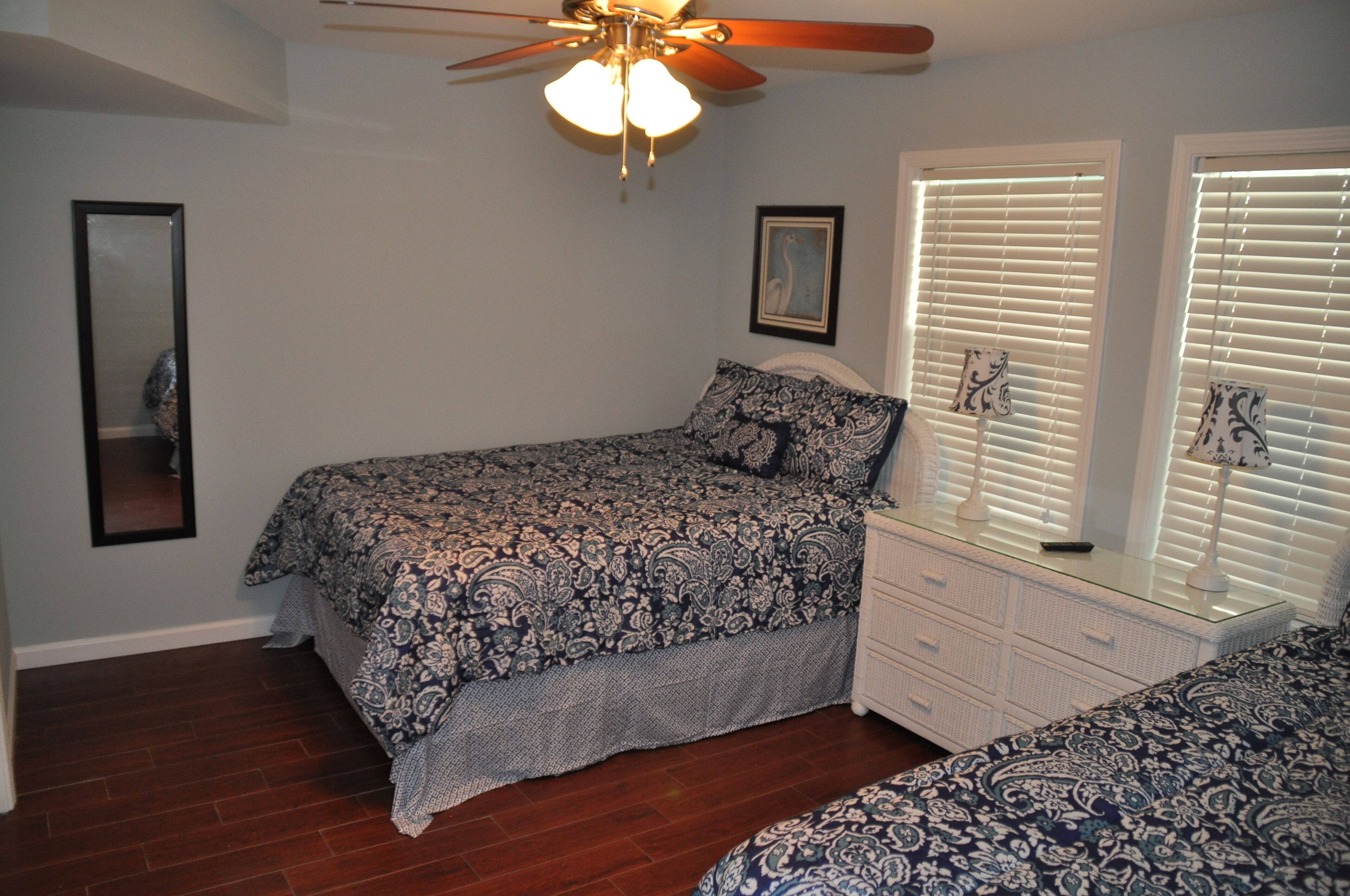 A bedroom with a bed, dresser, and ceiling fan.