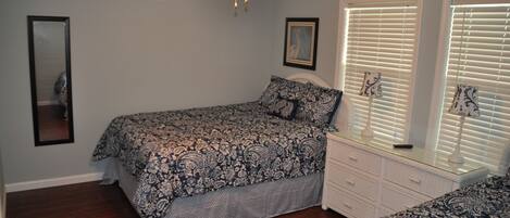 A bedroom with a bed, dresser, and ceiling fan.
