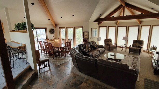 A spacious living room with a large brown leather sofa, a coffee table, and a dining area with wooden chairs and a table. - 3500 Sq Ft Home 4 Suites Pool Table, Hot Tub, Bikes, EV Charger, 4th Night Free! (Bend)
