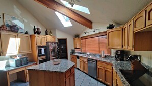 A spacious kitchen with wooden cabinets, a granite countertop, and a skylight. - 3500 Sq Ft Home 4 Suites Pool Table, Hot Tub, Bikes, EV Charger, 4th Night Free! (Bend)