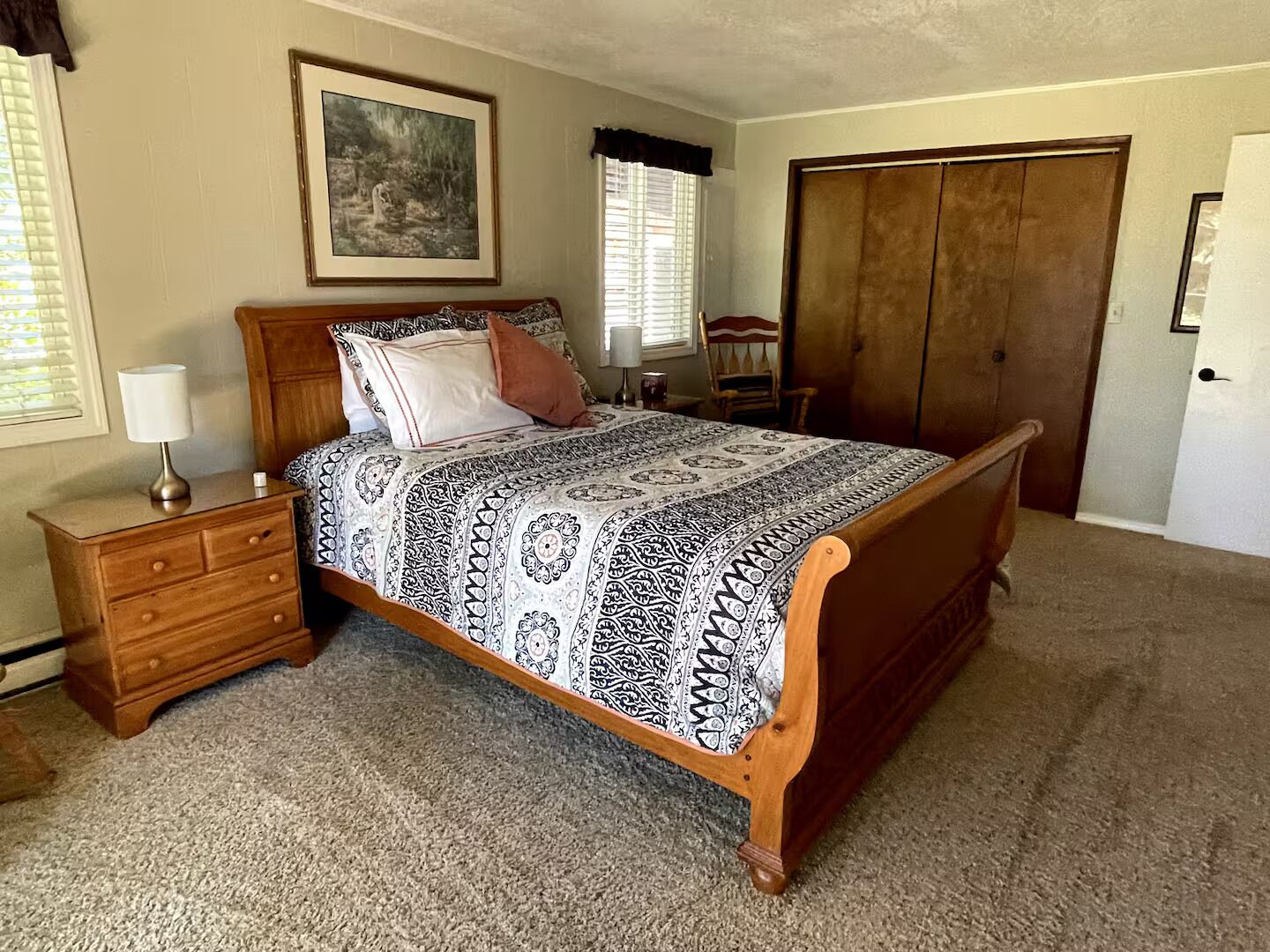 Une chambre à coucher comprenant un lit, une table de chevet, une commode et une grande armoire.