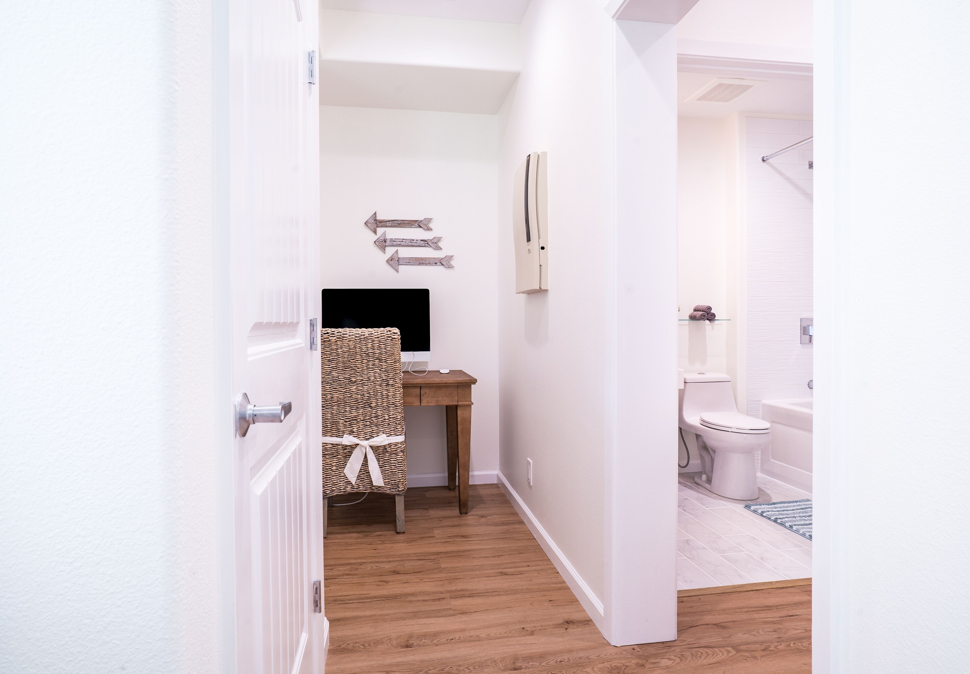 A narrow hallway leading to a bathroom with a toilet and a bathtub.