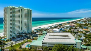 Un hôtel de grande hauteur, avec de nombreux étages, un parking et une vue sur la plage.