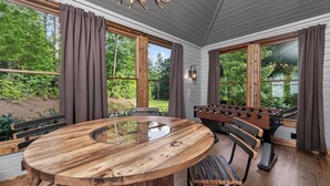 Ein Holztisch mit Glasplatte, ein Tischfußballspiel und eine Bank.