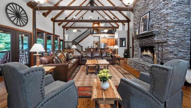 Ein geräumiges Wohnzimmer mit Kamin aus Stein, Ledersofas und Holzboden.