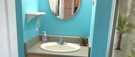 A bathroom with a sink, mirror, and wooden cabinets.