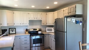 A kitchen with white cabinets, stainless steel appliances, a microwave, and a refrigerator. - Direct access to the beach! (Plymouth)