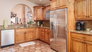 Una cocina con armarios de madera, un refrigerador de acero inoxidable y una cafetera.