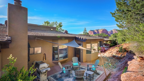 Una casa con un patio, muebles de exterior y una parrilla.