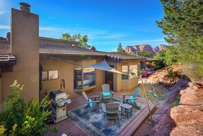 Une maison avec un patio, du mobilier d’extérieur et un barbecue.