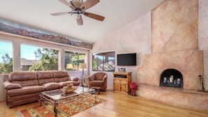 Una sala de estar con chimenea, sofá de cuero y televisor.