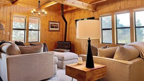 A cozy cabin interior with wooden walls, a fireplace, and a sofa.