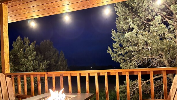 A deck with a built-in fire feature, wooden railings, and outdoor seating.