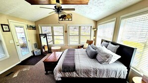 Ein Schlafzimmer mit einem großen Bett, einem Deckenventilator und mehreren Fenstern.