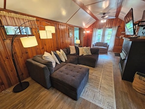 A cozy living room with a sectional sofa, a flat-screen TV, and a wooden interior.