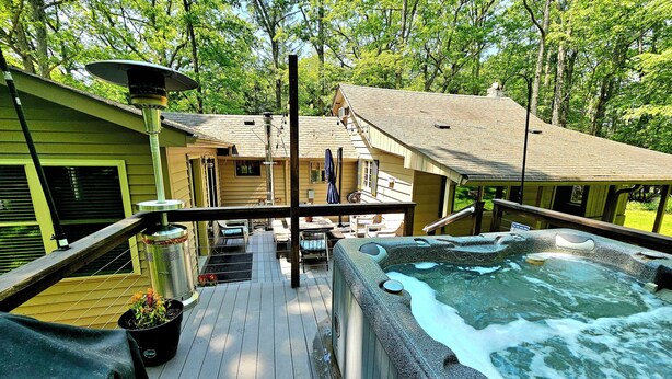 Eine Holterrasse mit Whirlpool, einer überdachten Terrasse und Blick auf ein Haus mit geneigtem Dach.
