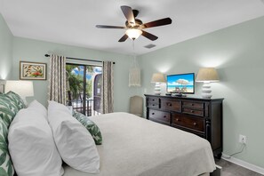 A bedroom with a bed, a ceiling fan, a TV, and a dresser.
