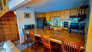 A kitchen with wooden cabinets, a granite countertop, and a dining area with wooden chairs.