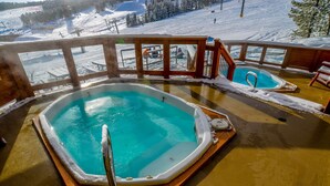 A hot tub on a deck with a snowy landscape in the background.