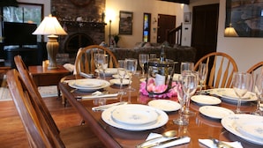 A dining room with a wooden table set for a meal, surrounded by chairs.