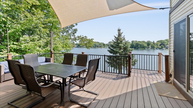 A deck with a table and chairs, overlooking a lake. - West Bend Lake House-Sleeps 12- Pontoon Avail-Full Pickleball & Basketball Court (West Bend)