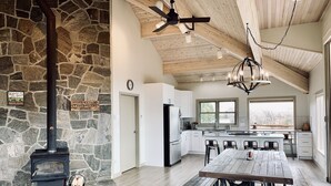 Una cocina amplia con pared de piedra, techo de madera y una gran mesa de comedor con sillas.