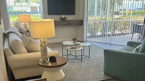 Een woonkamer met een bank, salontafel, lamp en plafondventilator.
