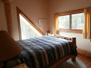 Un dormitorio con cama, ventana con cortinas y cabecera de madera.