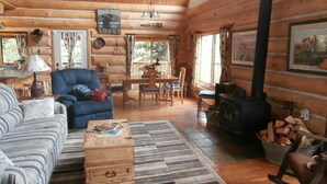 A cozy log cabin interior with a sofa, armchair, dining table, and a fireplace. - Exclusive 23-Acre Rocky Mtn. Retreat - Featured in a Music Video!  Unforgettable (Fairplay)