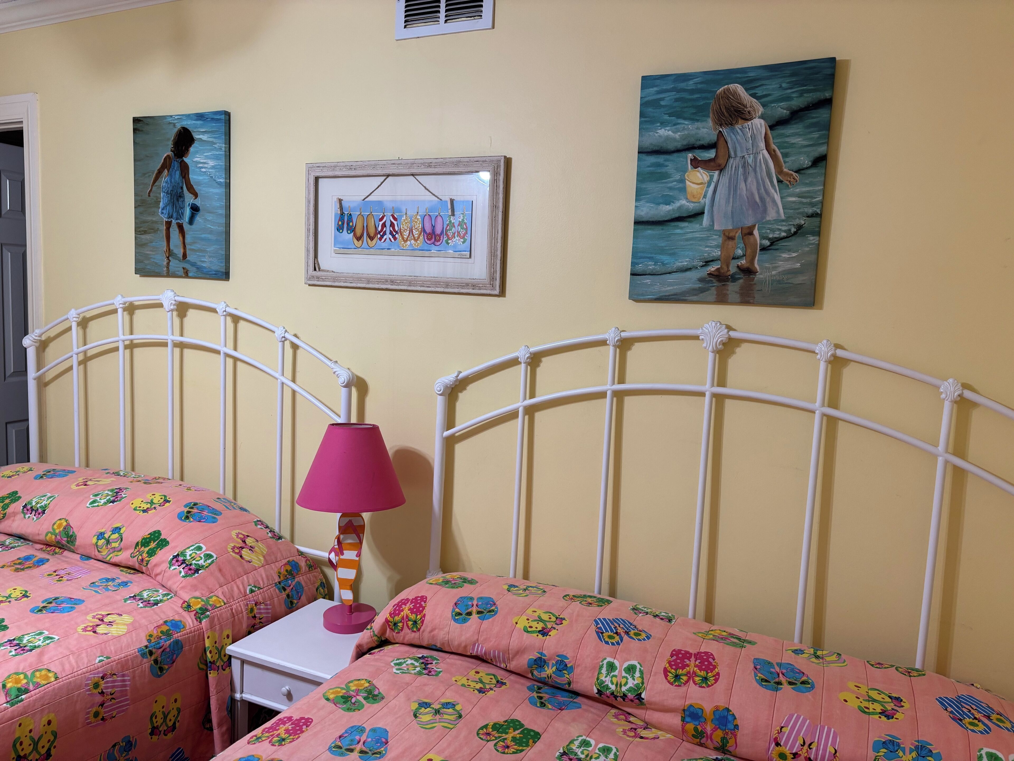 Une chambre avec deux lits, une table de chevet, une lampe et des œuvres d’art murales.