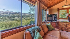 A living room with a large window offering a view of a hilly landscape. - Carmel Valley Village, close to Big Sur, Pebble, Carmel, & Monterey (Carmel Valley)