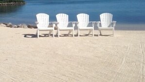Een strand met vier witte stoelen op een rij, gericht op de oceaan.