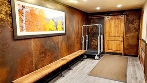 A hallway with a wooden bench, a framed picture, a metal cart, and a wooden door. - Ski-In/Ski-out  - 50 ft from SuperBee Lift (Copper Mountain)